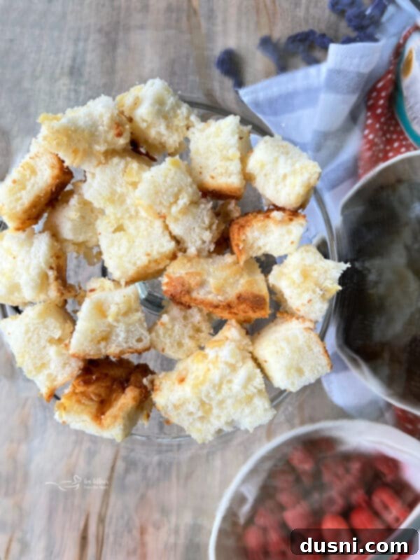 The first layer of cubed angel food cake placed evenly at the bottom of a clear trifle dish.