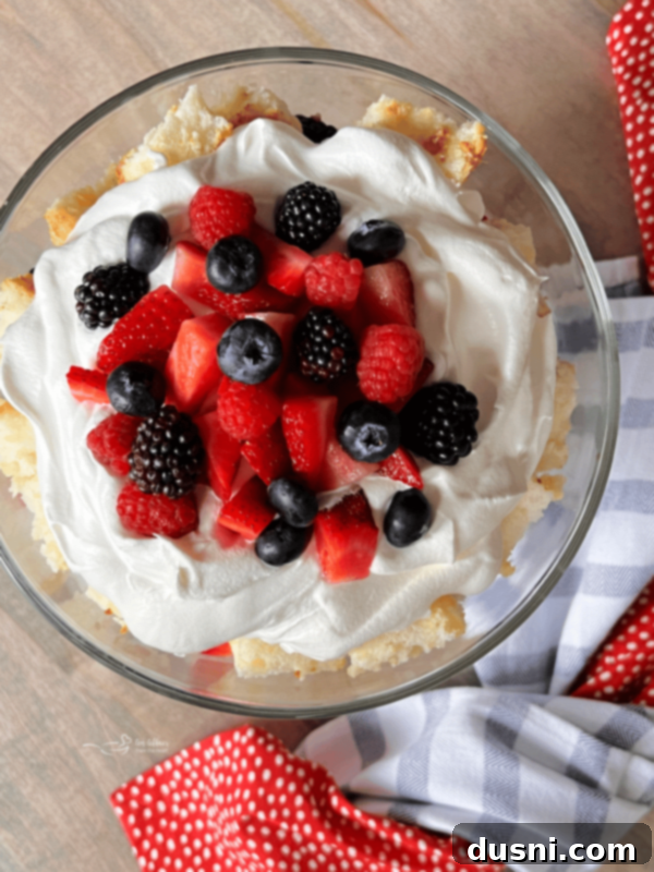 The finished Berry Trifle with a tall mound of whipped cream and abundant fresh berries on top.