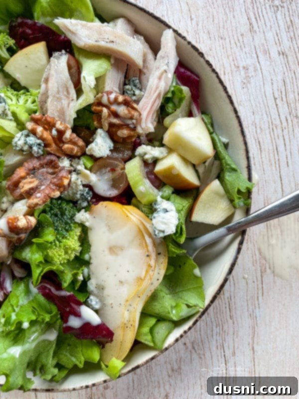 Chicken Waldorf Salad Overhead view of a beautifully plated Waldorf salad with grilled chicken, walnuts, apples, grapes, and pears, showcasing its vibrant colors and textures.