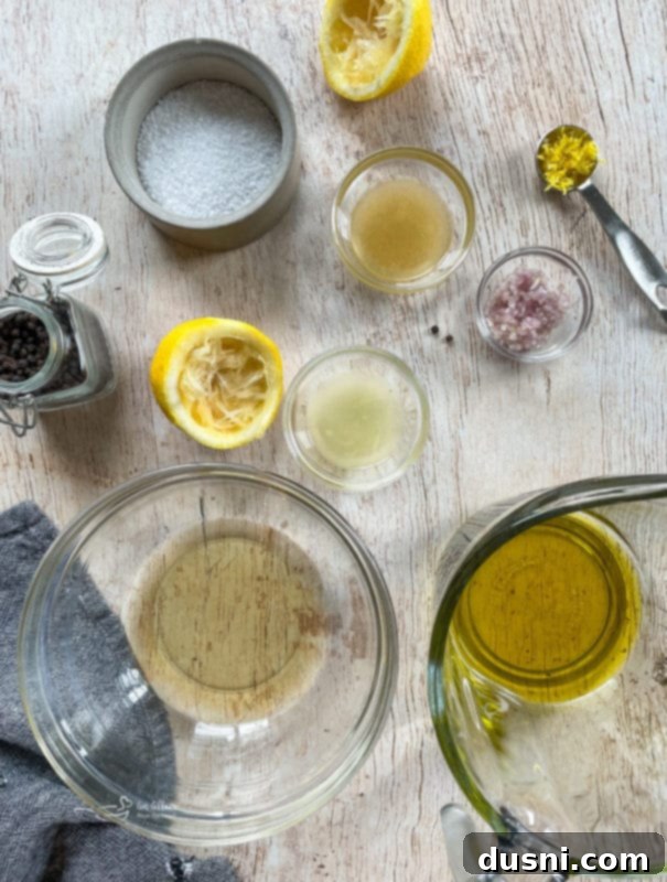 Waldorf Salad from Scratch Various ingredients for the white balsamic vinaigrette dressing, including olive oil, white vinegar, honey, shallots, and lemon, arranged in small bowls on a wooden surface.