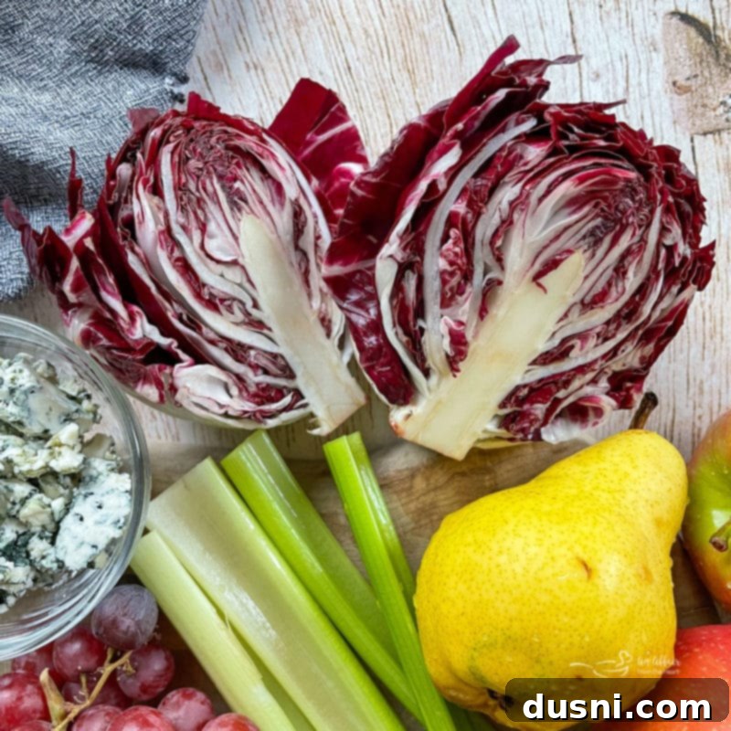 Chicken Waldorf Salad A close-up of fresh salad components including crisp radicchio, vibrant green celery, a sliced ripe pear, and crumbles of tangy blue cheese.