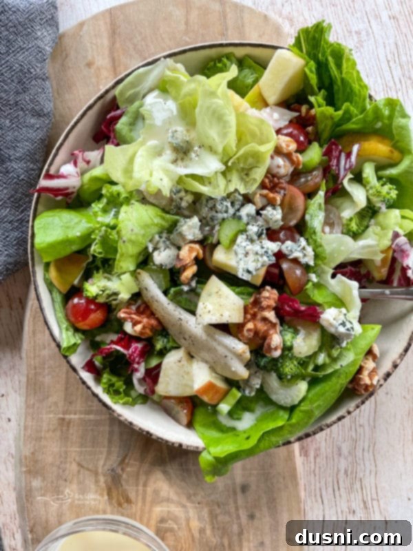 Chicken Waldorf Salad Top-down view of a colorful Waldorf salad in a white bowl, generously topped with fresh fruits, leafy greens, and succulent grilled chicken pieces, ready to be enjoyed.