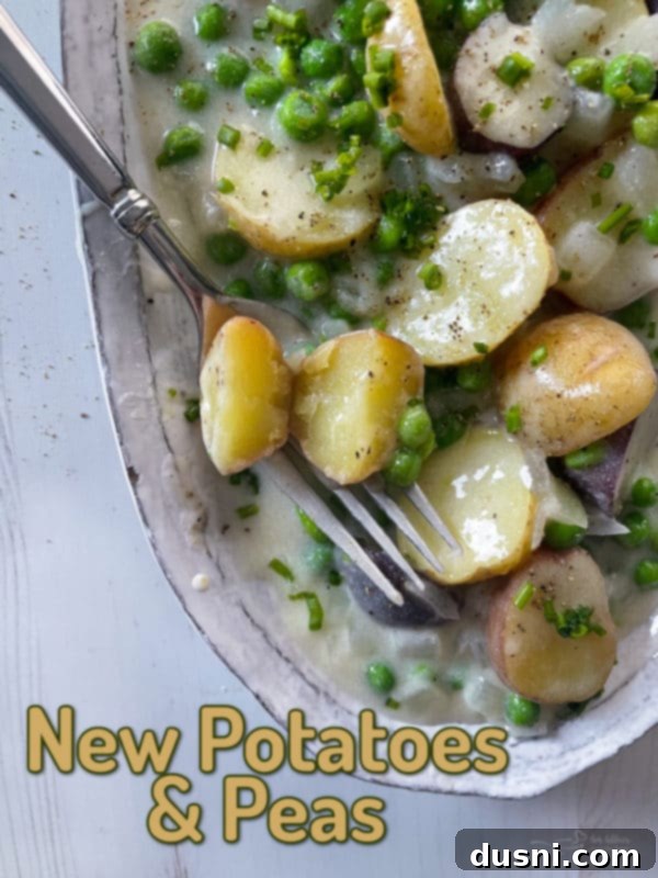 Top-down view of a baking dish filled with cooked potatoes and peas in a rich white sauce, garnished with herbs.