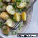 new potatoes and peas with fork in dish