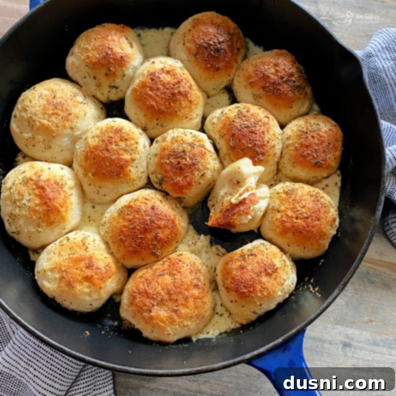 A cast iron skillet filled with Italian Cheese Bombs and a bowl of marinara sauce in the center