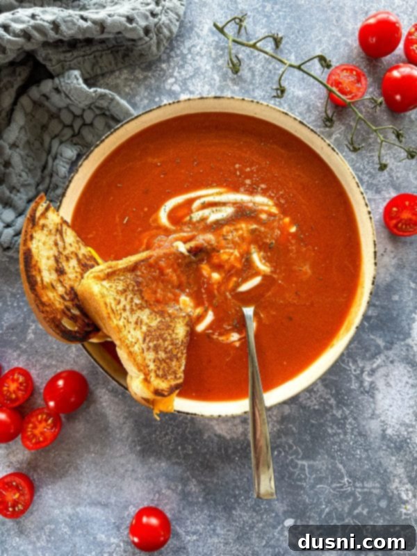 A bowl of creamy fire-roasted tomato soup with a grilled cheese sandwich next to it.