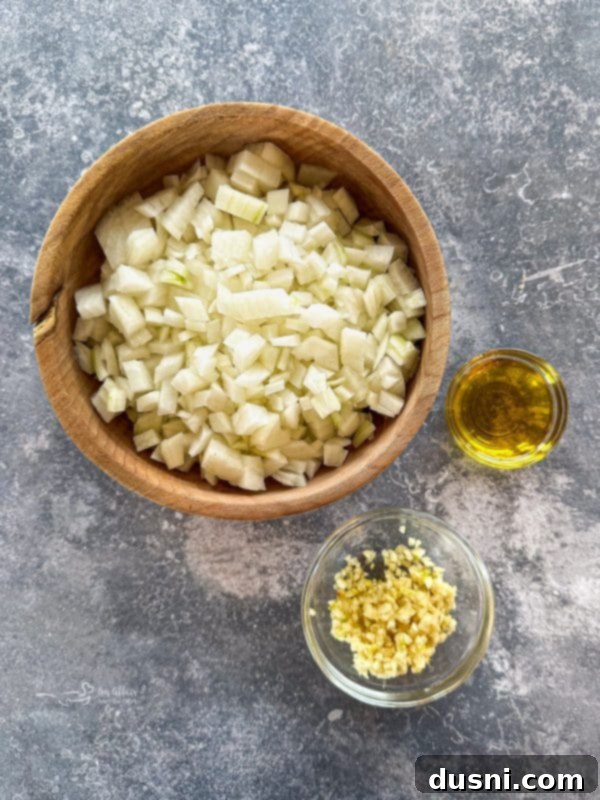 Assortment of canned tomatoes, onions, garlic, and other ingredients for tomato soup on a countertop.