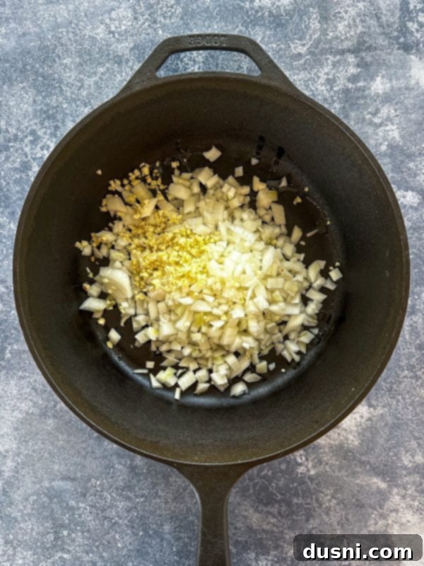 Onions and garlic being sautéed in a large Dutch oven.