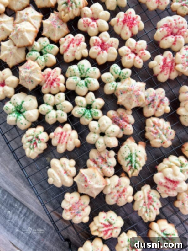 Overhead shot of freshly baked spritz cookies with colorful sprinkles on a wire cooling rack