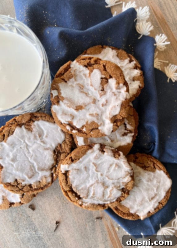 Chewy Iced Molasses Cookies A selection of chewy iced molasses cookies artfully arranged on a rustic blue linen, highlighting their delightful texture.