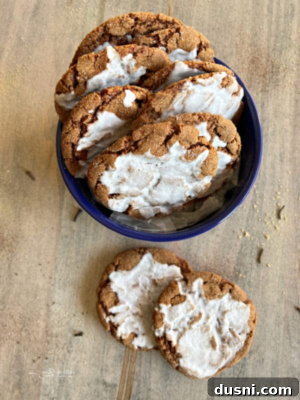 Old-Fashioned Iced Molasses Cookies A close-up view of freshly baked old-fashioned iced molasses cookies, artfully arranged in a rustic blue bowl, with a scattering of powdered sugar.