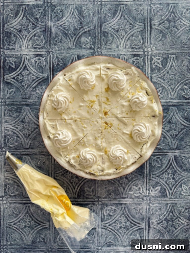 Effortless Lemon Dream Pie 12 Close-up of a slice of Lemon Icebox Pie topped with piped whipped cream and lemon zest.