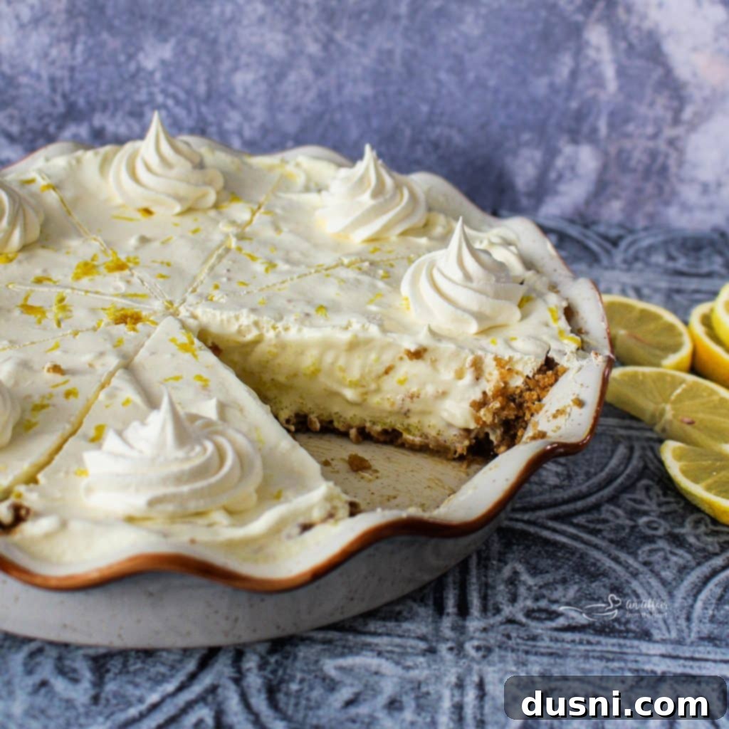 Effortless Lemon Dream Pie 5 A wide shot of a whole Lemon Icebox Pie, with two slices already removed, on a rustic wooden surface, garnished with fresh lemon slices.