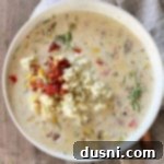 Creamy Sweet Corn & Cheddar Chowder 19 Cheesy Potato Corn Chowder with a copper-colored spoon and tan napkin