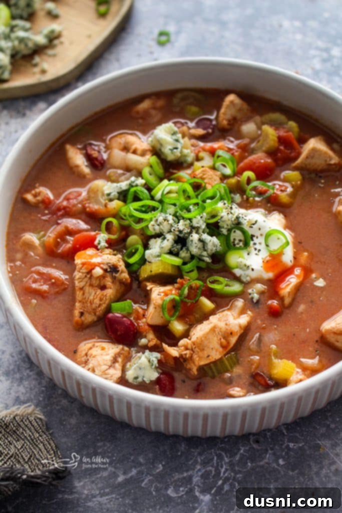 Hearty Slow Cooker Buffalo Chicken Chili 2 A steaming bowl of Slow Cooker Buffalo Chicken Chili, topped with green onions and a dollop of sour cream, ready to be enjoyed.