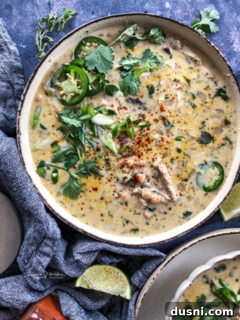 Hearty Slow Cooker Buffalo Chicken Chili 12 Overhead shot of a bowl of creamy White Chicken Chili, garnished with fresh cilantro and cheese.