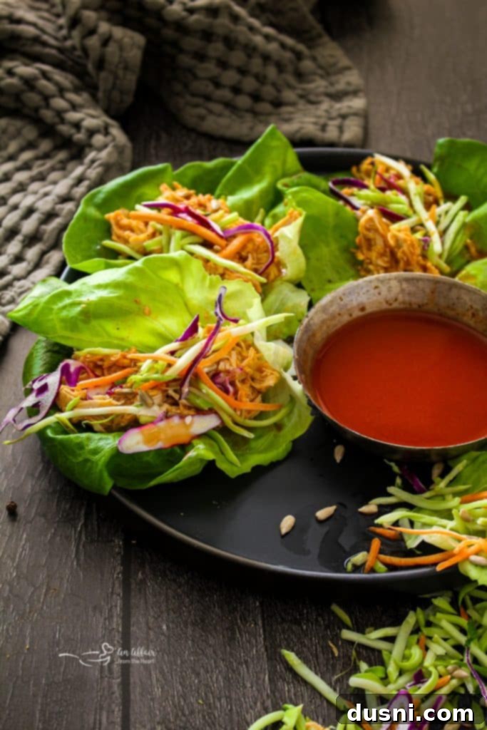 Hearty Slow Cooker Buffalo Chicken Chili 14 Close up of vibrant Buffalo Chicken Lettuce Wraps, filled with chicken, shredded carrots, and a drizzle of sauce.