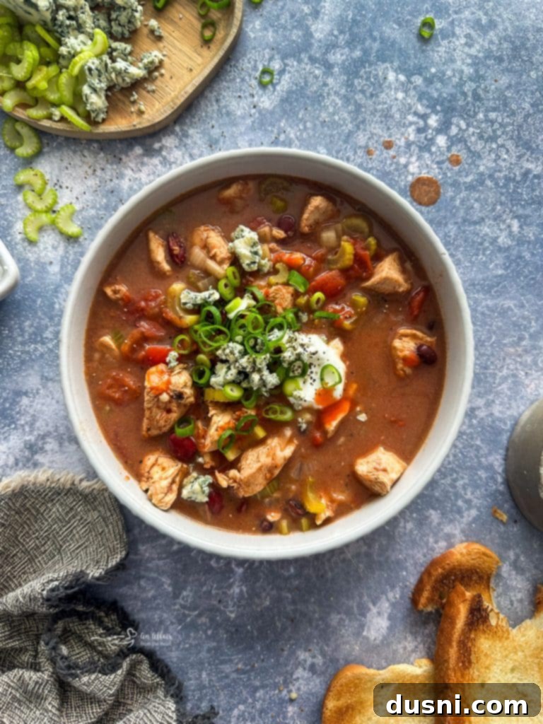Hearty Slow Cooker Buffalo Chicken Chili 8 Delicious Slow Cooker Buffalo Chicken Chili being served into bowls from the crockpot, ready for toppings.
