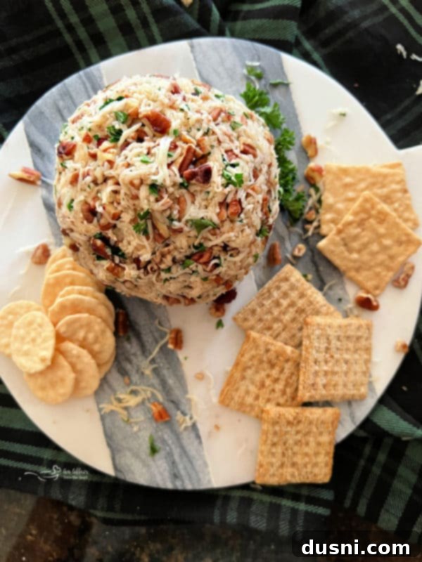 Overhead shot of Dorothy's Holiday Cheese Ball on a platter with crackers, ready to be served.