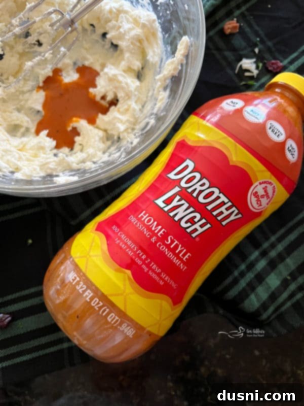 A bottle of Dorothy Lynch Home Style dressing prominently displayed beside fresh ingredients like parsley and cream cheese.