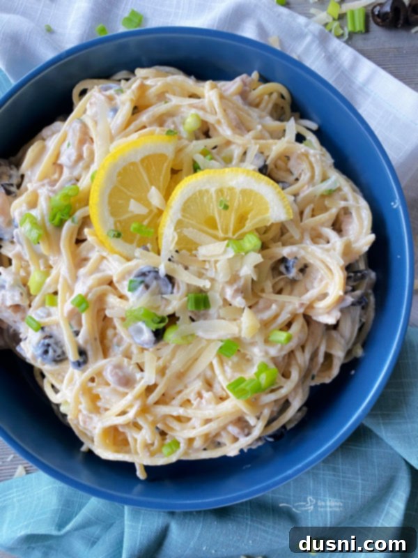 Top view of creamy tuna spaghetti served in a bowl, garnished with a lemon wedge and fresh parsley