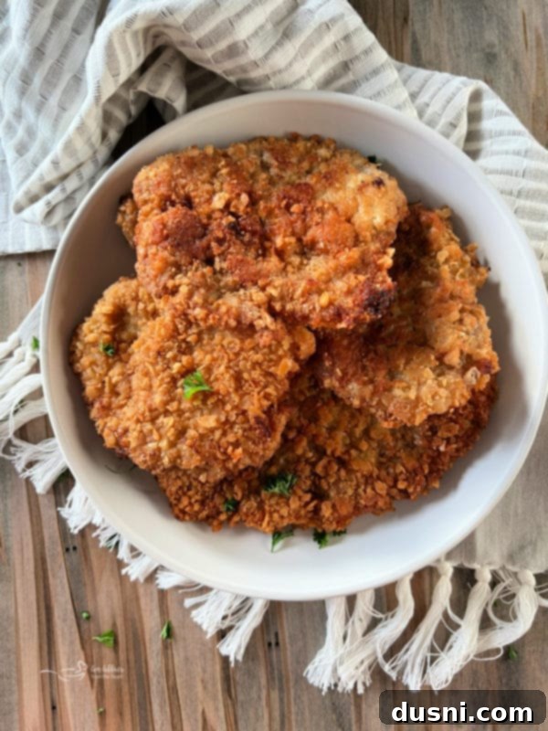 Two crispy breaded pork cutlets on a plate, garnished with parsley.