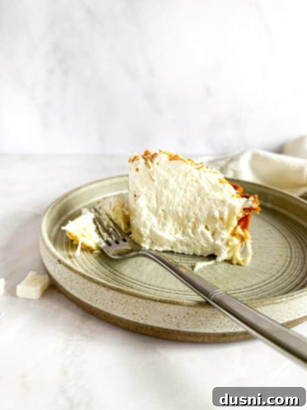 Homemade Coconut Cream Pie slice with whipped cream and toasted coconut