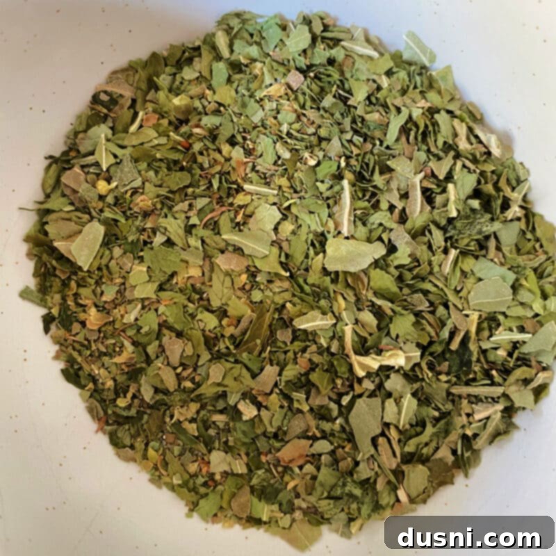 Hands mixing Italian herbs and spices in a small bowl