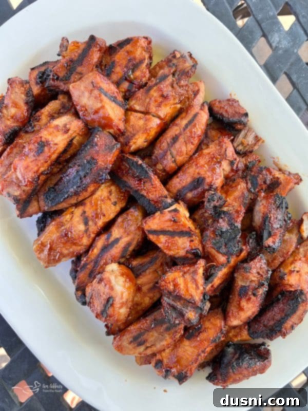 Three racks of BBQ pork ribs stacked on a cutting board, garnished with fresh herbs