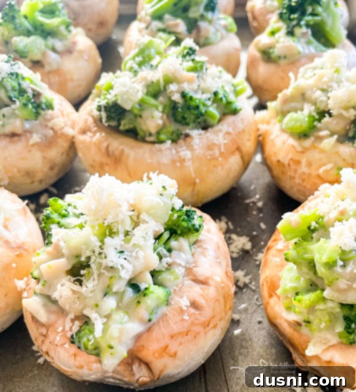 The Best Stuffed Mushrooms A close-up of a plate of baked broccoli stuffed mushrooms, highlighting their golden-brown cheese topping.