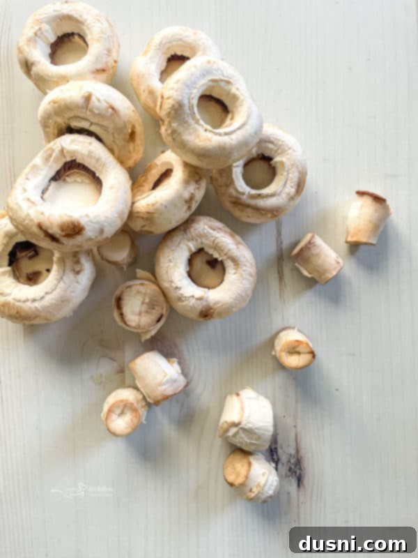 Broccoli Stuffed Mushroom Caps Clean white mushrooms arranged on a white surface, ready for stuffing.