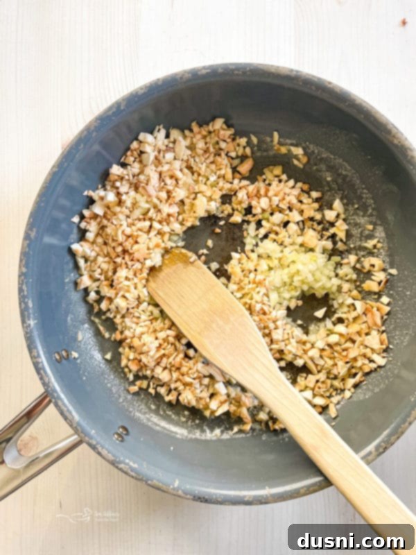 Baked Stuffed Mushrooms A frying pan with sautéed mushroom stems and diced onion, forming the base of the filling.