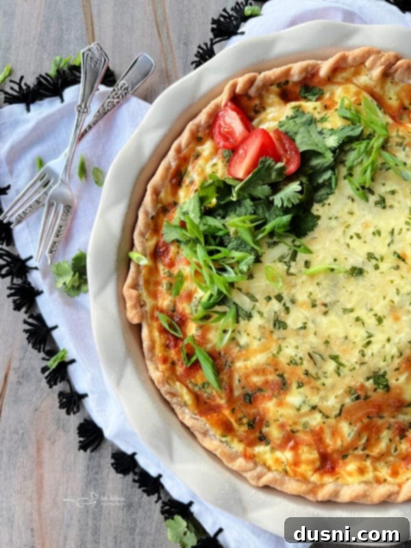Slice of Green Chile Quiche with Sausage on a plate with fresh greens