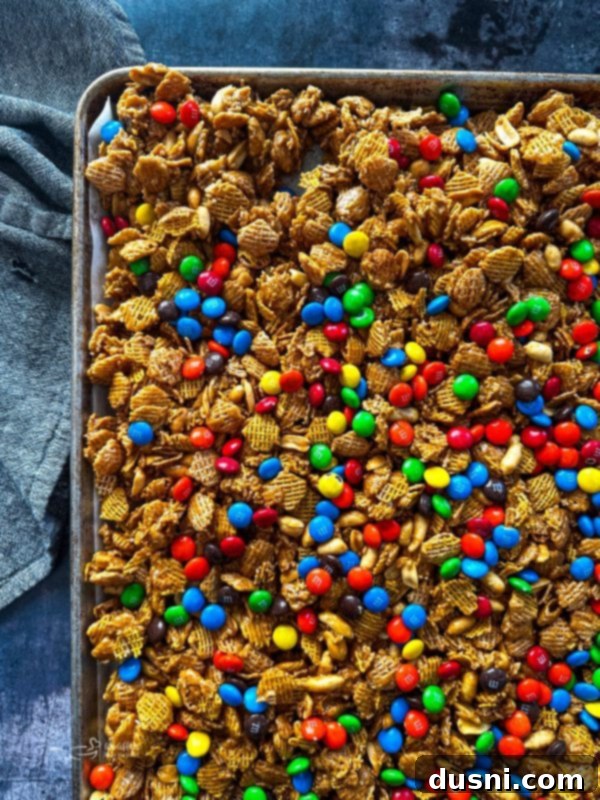 Candy Coated Crispix Mix spread out on a baking sheet, freshly baked and ready to cool.