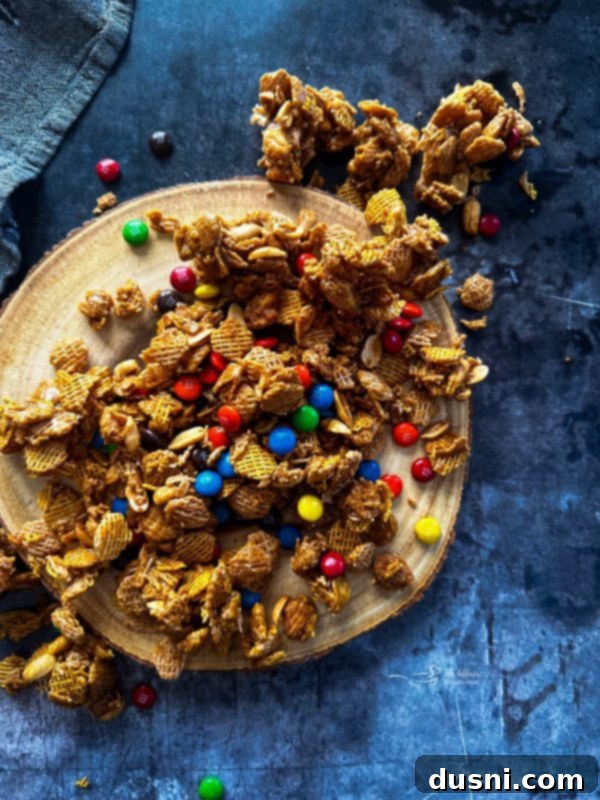 A hand reaching for a handful of Candy Coated Crispix Mix from a white bowl.