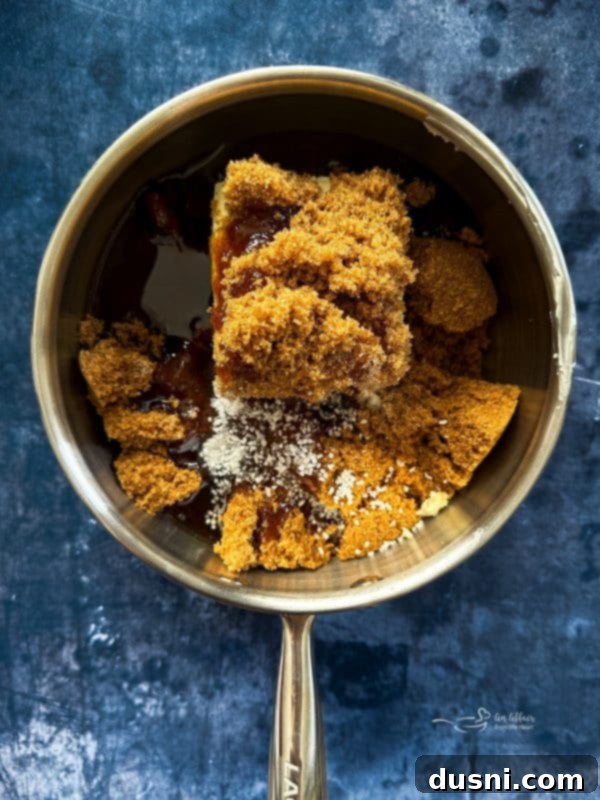 Close-up of butter, brown sugar, corn syrup, and salt in a saucepan, beginning to melt on the stove.