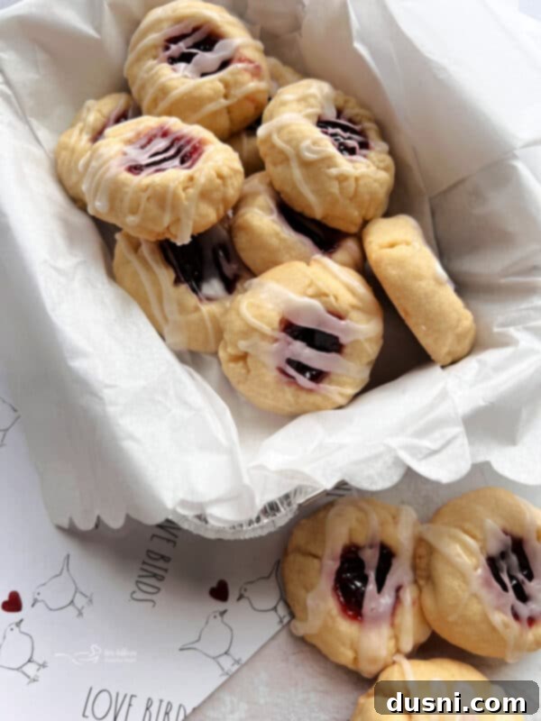 Raspberry Almond Shortbread Jewels 16 A few freshly baked almond raspberry thumbprint cookies stacked on a wire cooling rack