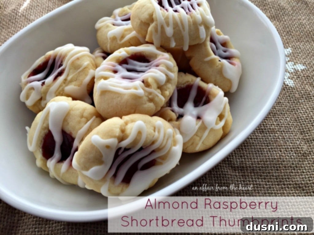 Raspberry Almond Shortbread Jewels 17 A beautifully arranged plate of almond raspberry shortbread thumbprints, showcasing their glaze and jam centers