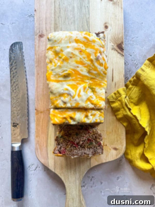 Mexican cheese sprinkled on top of a partially baked meatloaf