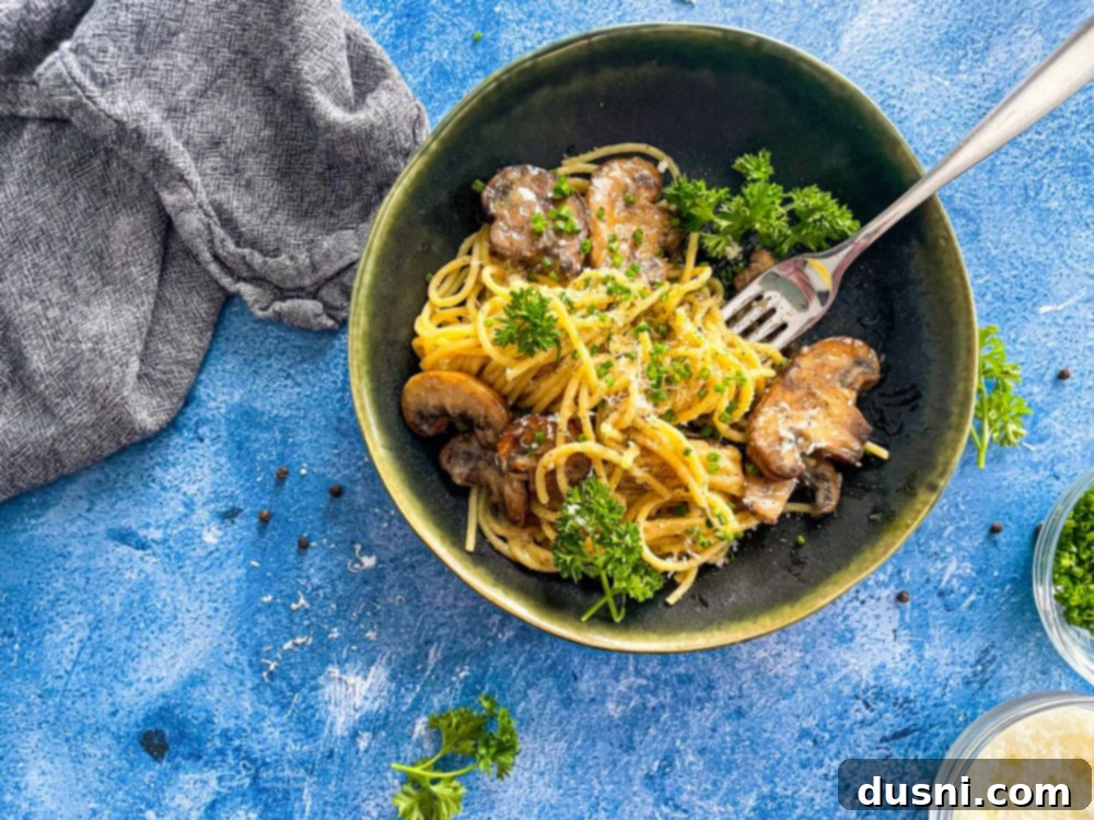A close-up shot of a single serving of Cacio e Pepe pasta with sautéed mushrooms, highlighting the creamy sauce.
