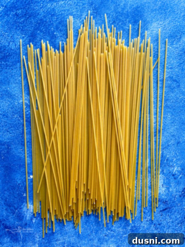 Uncooked spaghetti noodles arranged for a photo, representing the essential pasta component of Cacio e Pepe.