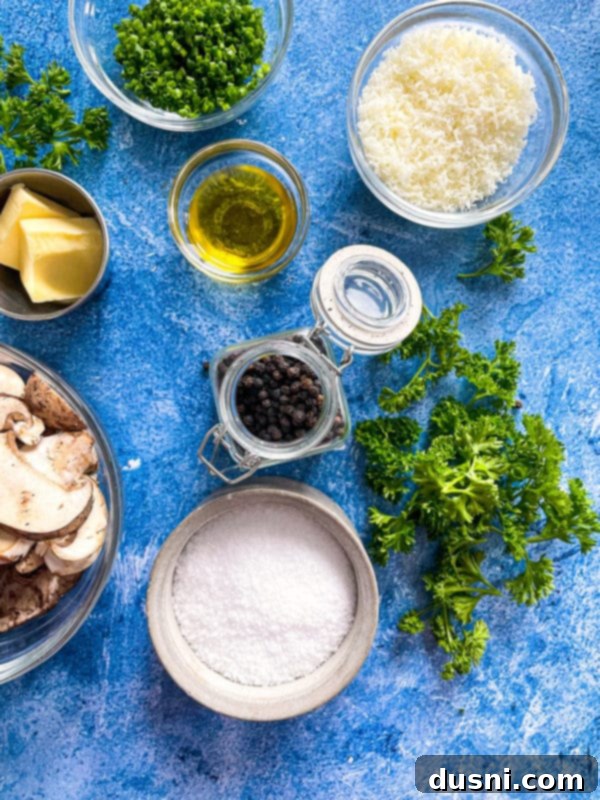 A flat lay of ingredients for Cacio e Pepe with Mushrooms, including Parmesan, herbs, oil, salt, pepper, butter, and sliced mushrooms.