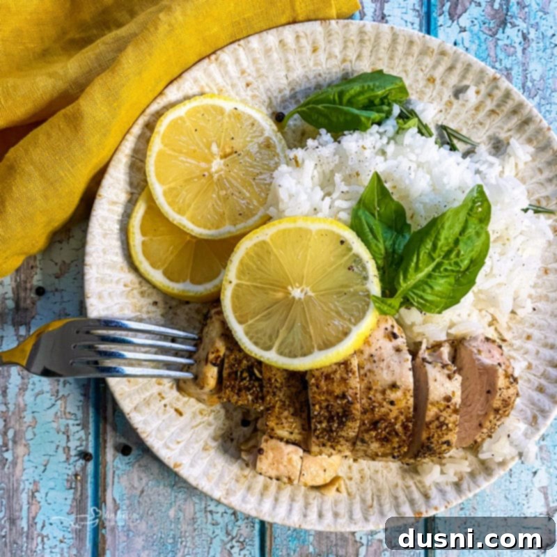 An overhead shot of lemon pepper chicken served with rice, fresh lemon slices, and basil, ready to be enjoyed.