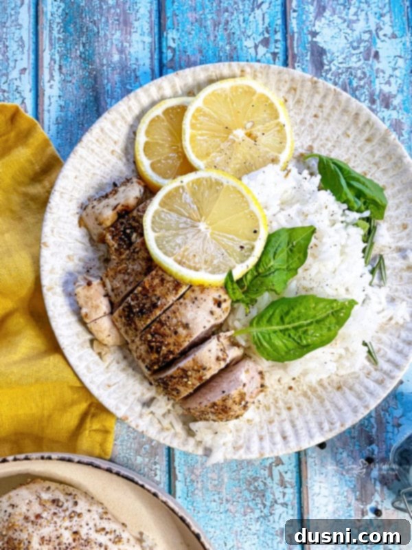 Two plates of lemon pepper chicken, one with rice and basil, another with just chicken, showcasing the dish's versatility and appetizing presentation.