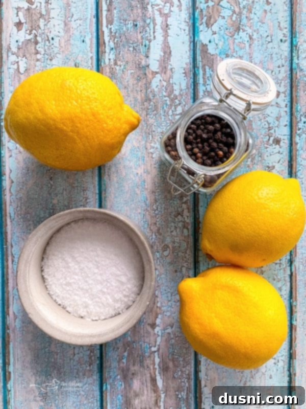 Three fresh lemons, whole black peppercorns, and coarse salt, essential ingredients for making homemade lemon pepper seasoning from scratch.