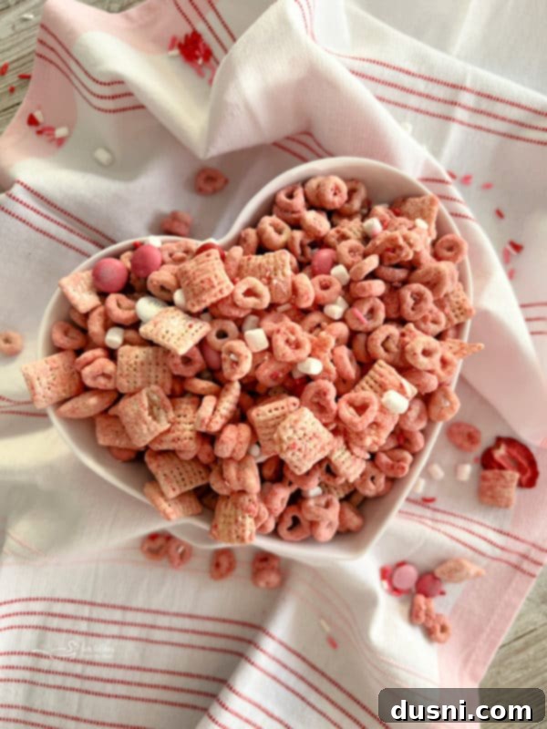 Strawberry White Chocolate Cereal Crunch 2 White Chocolate Strawberry Muddy Buddies in a bowl, a delicious dessert or snack for Valentine's Day or any festive occasion.