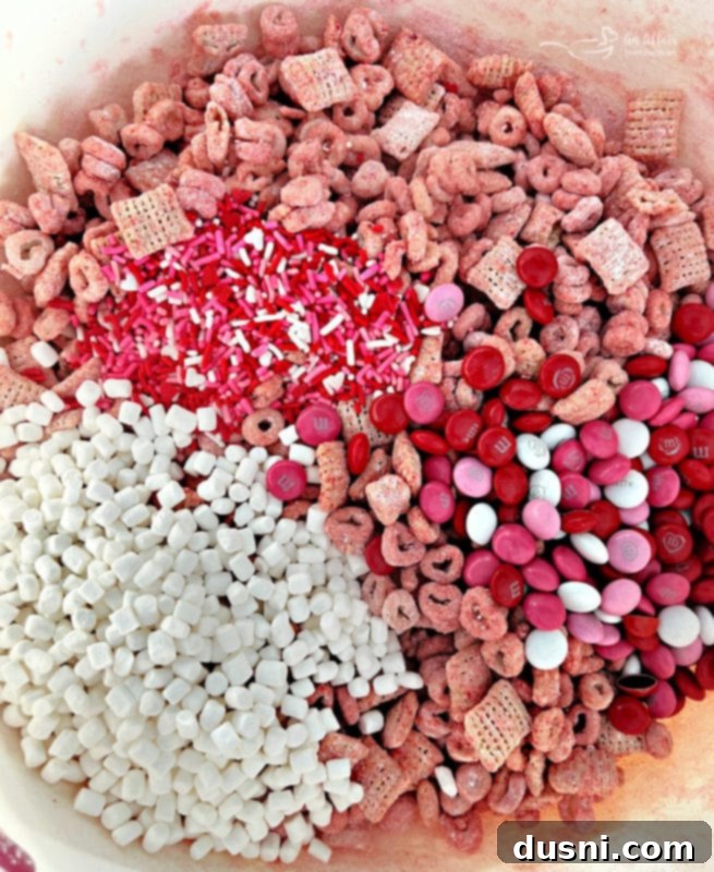 Valentine's Day Chex Mix Ingredients for pink Valentine's Day puppy chow: cereal, M&M's, sprinkles, and mallow bits.