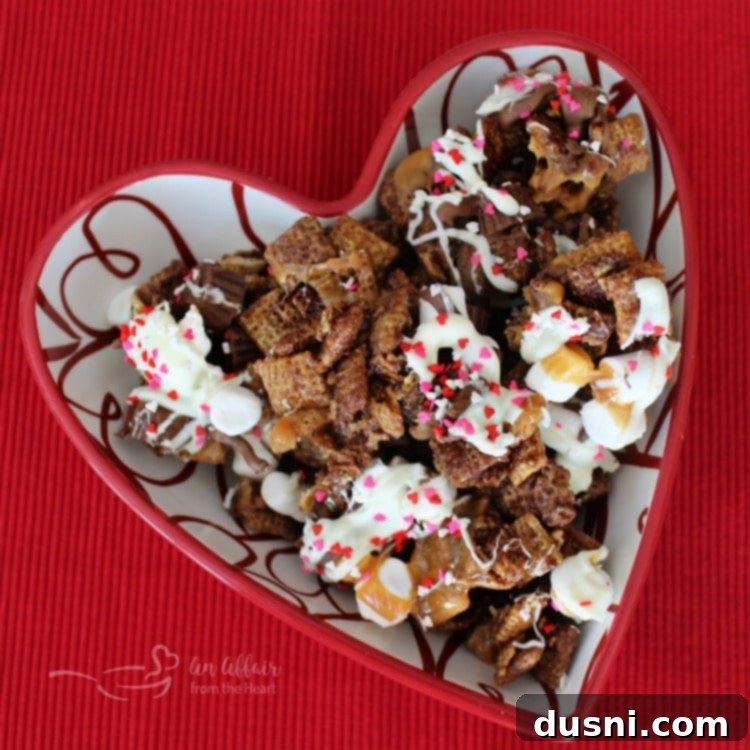 Strawberry White Chocolate Cereal Crunch 11 Overhead shot of a heart-shaped bowl filled with Better Than Sex Chex Mix, a rich and decadent treat.