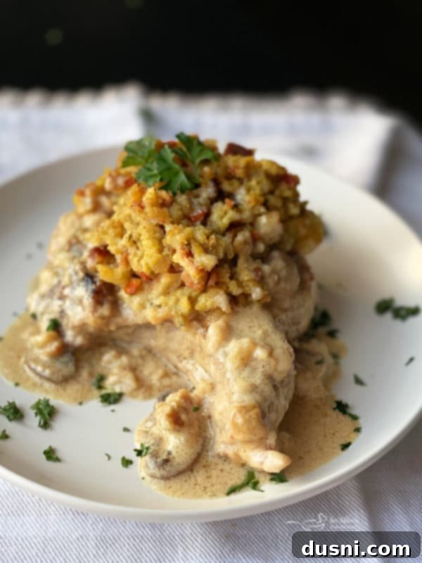 Sunrise Sliders 16 A white plate with a baked pork chop topped with stuffing and mushroom gravy, presented beautifully.