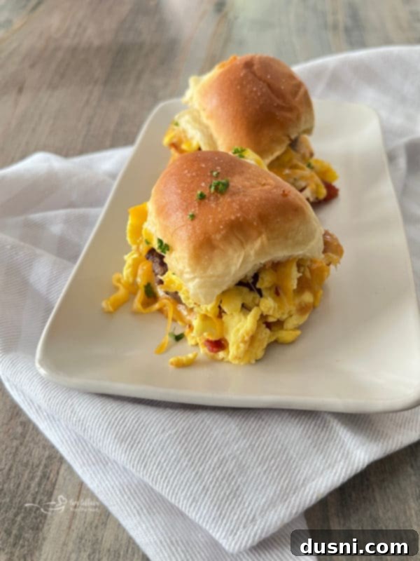 Sunrise Sliders 4 Two breakfast sliders on a white plate, showcasing the golden Hawaiian rolls and layers of delicious fillings.